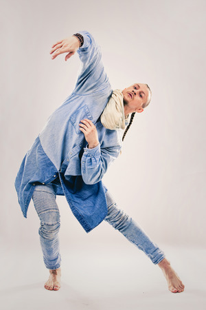 Caucasian male dancer wearing blue denim shirt and pants on light background performing hip hop and contemporary style dance.の写真素材