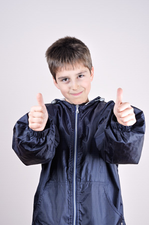 Young boy wearing blue jacket with thumbs upの写真素材