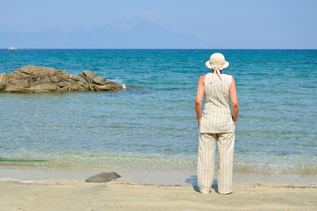 Woman wearing a hat standing on the sandy beachの写真素材
