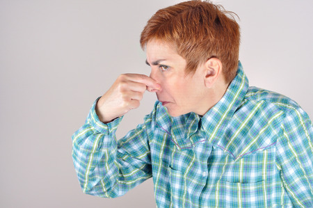Profile of a woman holding her nose with her fingers because of  bad  smellの写真素材