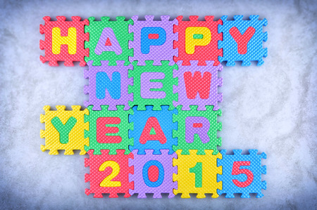 Happy New Year 2015 sign made out of alphabet and numbers puzzle pieces isolated on icy backgroundの写真素材