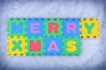Merry Christmas sign made out of alphabet puzzle pieces isolated on icy backgroundの写真素材