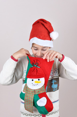Cute young pleasantly surprised boy looking inside Christmas stockingの写真素材
