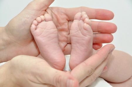 Feet of a newborn baby girl in the hands of a mother