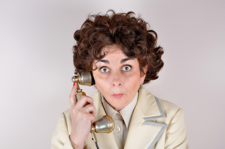 Surprised woman making a phone call on the retro telephoneの写真素材