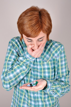 Woman holding and looking at a bunch of drugs in one hand and covering her mouth with the other handの写真素材