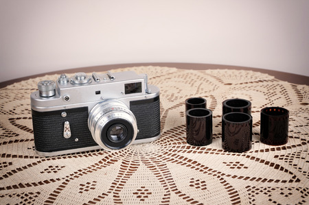 Retro camera and films on the brown table with handmade tablecloth. Vintage style photo