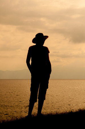 Silhouette of the woman standing on the hill near the seaの写真素材