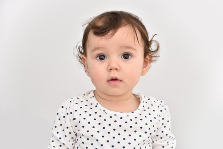 Portrait of a cute baby girl with beautiful big brown eyes. Isolated on a light gray background.の写真素材