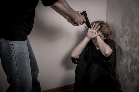 Aggressive man threatening frightened woman with the gunの写真素材