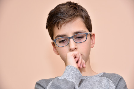 Thoughtful cute young boy with glassesの写真素材