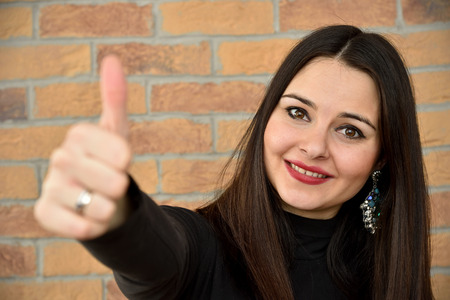 Beautiful young woman with thumb up. Selective focus.の写真素材