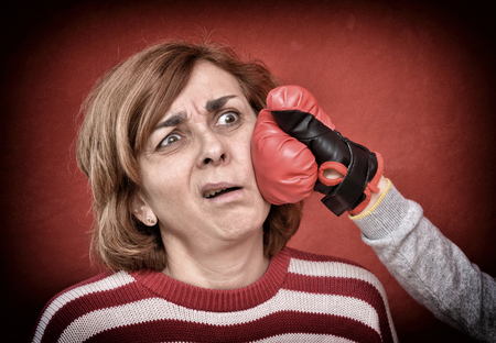 Woman being punched with red boxing glove in her face. Computer added  dust, scratches, grain and vignette.の写真素材