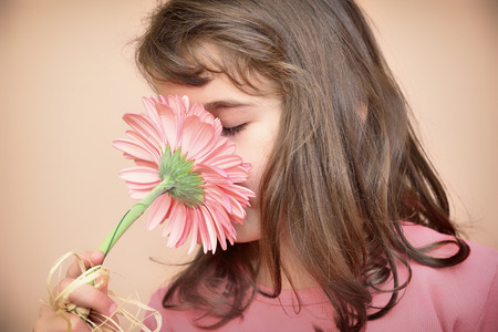 Cute young girl with closed eyes smelling a flowerの写真素材