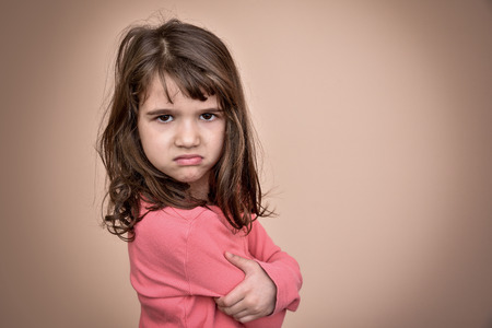 Angry and pouting cute young girl with crossed armsの写真素材