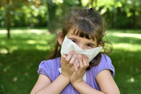 Young girl with allergy symptom sneezing in a tissueの写真素材