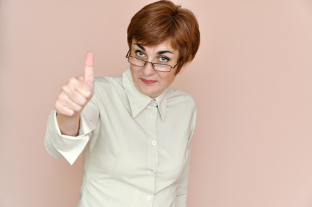 Smiling woman wearing glasses showing thumb up isolated on the orange brown color backgroundの写真素材