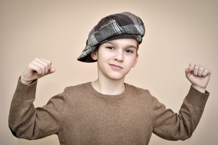 Cute young boy with cap showing his strong arms. Vintage style.の写真素材