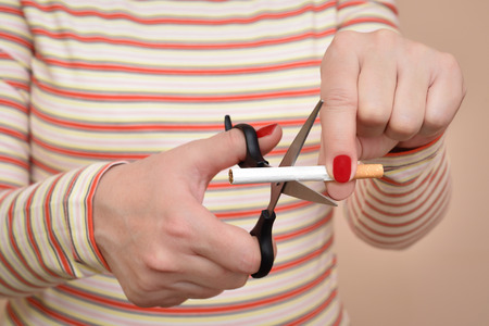 Hands of a woman cutting a cigarette with scissors. Stop smoking concept.の写真素材
