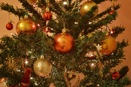 Christmas tree decorated with ornaments and blinking light bulbs. Ambient light. Selective focus.の写真素材