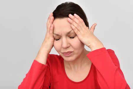 Woman with headache and closed eyes holding her head. Isolated on the background.の写真素材