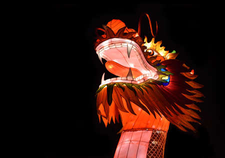 Chinese dragon lantern with bright glowing head isolated on the black background. Copy space on the...