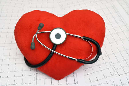 Red plush heart with stethoscope on the cardiogram charts in a paper form as a background. Health care and medical concept.の写真素材