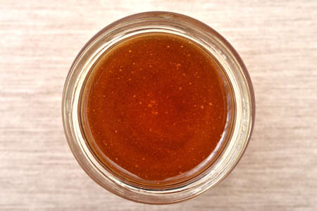 Sweet natural honey in a glass jar on the rustic wooden table. Close-up photo. Top view. Healthy food concept.の写真素材
