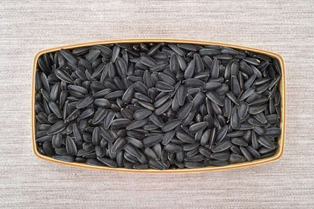 Black sunflower seeds in the wooden dish on the rustic wooden table. Top view.の写真素材