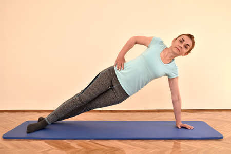 Middle-aged woman doing pilates exercises on the mat at home. Fitness, sport, training and healthy lifestyle concept.の写真素材