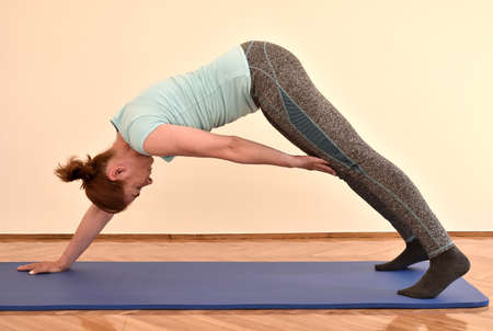 Middle-aged woman doing pilates exercises on the mat at home. Fitness, sport, training and healthy lifestyle concept.の写真素材
