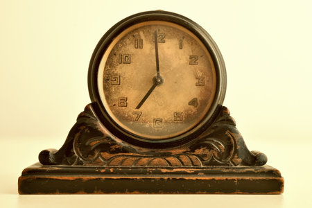 Old small wooden clock on the yellow table and pale yellow background. Close-up. Retro style photo.の写真素材