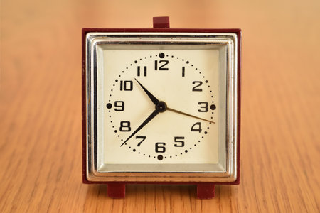 Old small clock on the brown wooden table. Close-up. Retro style photo.の写真素材