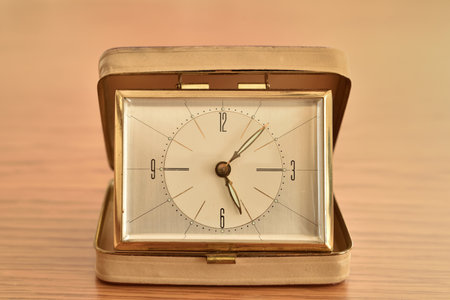 Old small clock on the brown wooden table. Close-up. Retro style photo.の写真素材