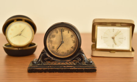Old small clocks on the brown wooden table. Close-up. Selective focus. Retro style photo.の写真素材