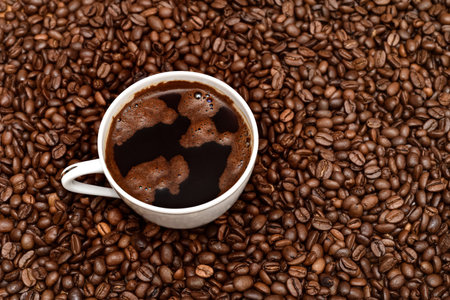 Cup of coffee and heap of fresh roasted coffee beans on the tableの写真素材