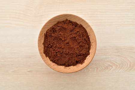 Coffee powder in the wooden dish on the light brown wooden table. Close-up. Top view.の写真素材