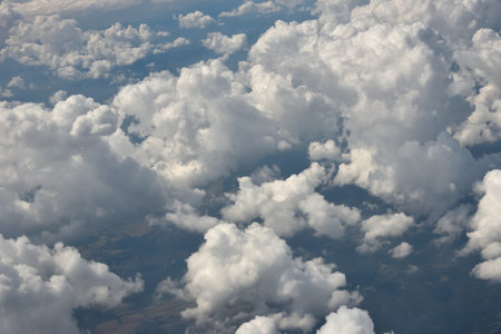 Aerial view of the thick and dramatic clouds from the airplane window. Airplane above clouds. Creative background for design. Flying, traveling and holidays concept.の写真素材