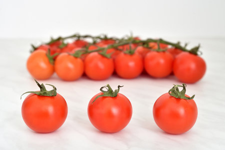 Cherry tomatoes on the light gray marble table texture. Close-up. Copy space. Selective focus.の写真素材