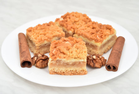 Pieces of homemade apple pie on the white plate decorated with walnut kernels and cinnamon sticks. Close-up. Selective focus.の写真素材