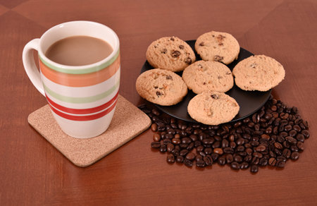 Cookies, coffee beans and mug of white coffee on the brown wooden table. Selective focus.の写真素材