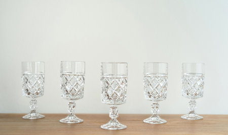 Elegant empty crystal glasses with high stem on the brown wooden table. Close-up. Copy space. Selective focus.の写真素材