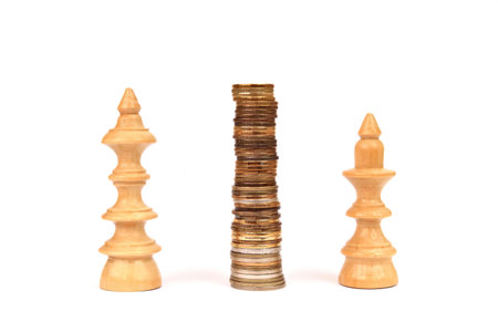 Stack of coins between the white wooden king and queen chess pieces on the white background. Copy space. Concept of business strategy, finance and saving money.の写真素材