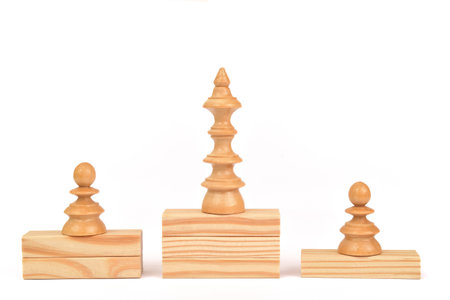 White wooden king and pawns chess pieces on the wooden blocks stacked in the shape of winner podium on the white background. Copy space. The best in the business concept.の写真素材