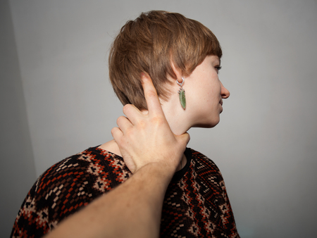 young woman is choked by man's handの写真素材