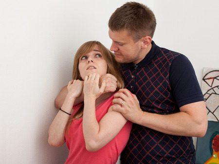 Violence against women in the family. Husband grabbed his wife by hands choking her.  The woman opened her mouth in pain.の写真素材