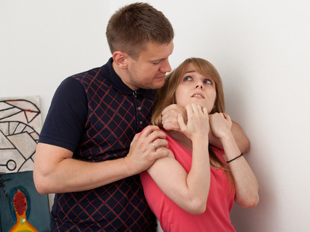 man's hand has  grabbed the woman's   neck from behind, strangling and causing her painの写真素材
