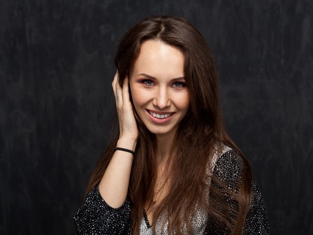 young brunette lady taking away hair by the hand on grey backgroundの写真素材