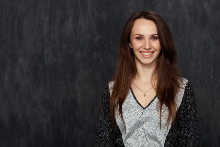 Studio portrait of a beautiful brunette woman with a big smile on dark backgroundの写真素材