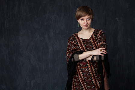 Young beautiful lady in poncho on grey backgroundの写真素材